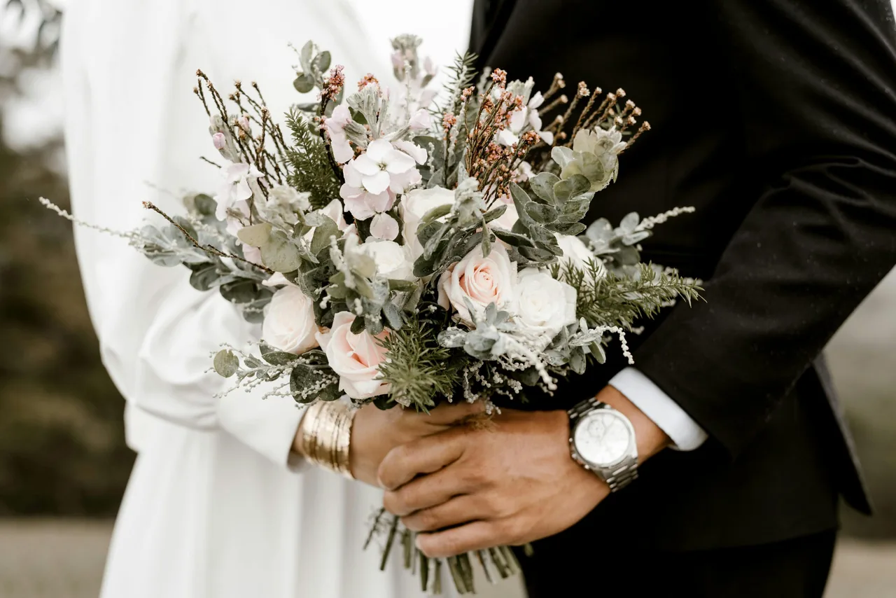 Pareja sosteniendo un ramo de flores claras